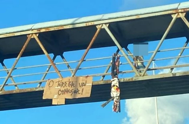 Boneco com uniforme da TUI é pendurado em passarela na Avenida Paralela
